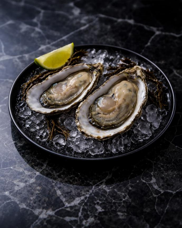 Duo d’huîtres premium sur glace, ambiance sombre gastronomique.